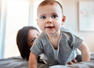 Fototapeta premium Baby, bed and play with mom for child development, bonding and crawl in home. Toddler, childhood and mother in house bedroom with motor skills, growth and support for health or wellness in apartment