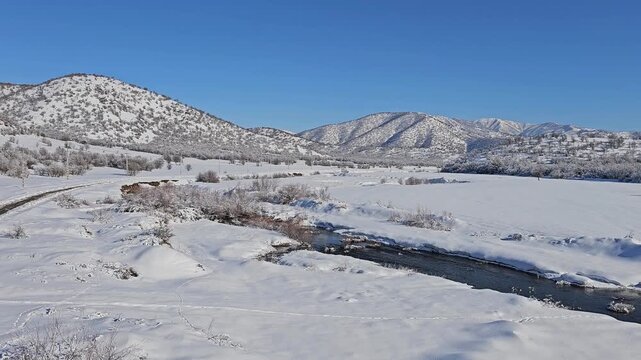 A winding river cutting through a snowy plain with distant mountains, highlighting the calm flow of water in a serene winter landscape.  
📍Marivan, Kurdistan 