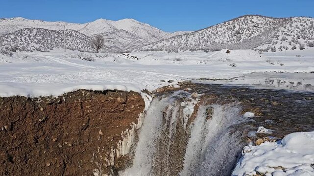 A winter waterfall drops from a snowy plain into a deep canyon, framed by distant Zagros mountains and forests surrounding the untouched white landscape.
📍Marivan, Kurdistan 
