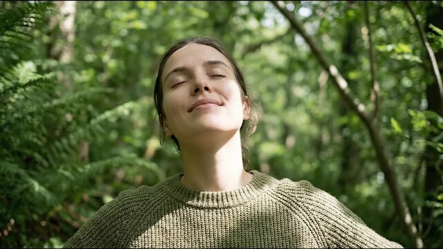 Young woman experiences peaceful, serene moment in vibrant green forest, finding deep happiness outdoors. Embracing natures beauty and soft sunlight, she fosters wellness and mindful connection