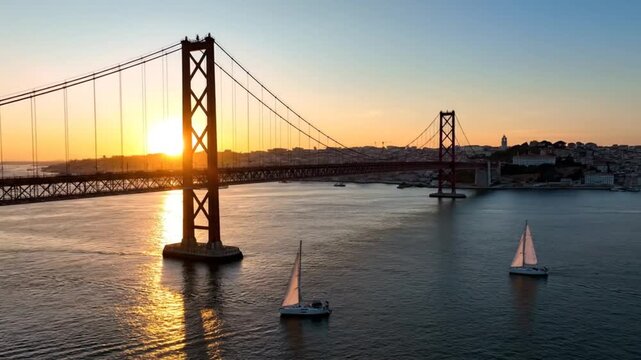 Stunning sunset view of the 25 de Abril Bridge in Lisbon with sailboats on the water