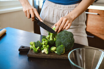 Preparation of smashed broccoli with cheese on a cutting board at home kitchen counter