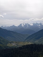 Stunning Mountain Landscape with Layered Green Hills, Distant Snowy Peaks and Valley Settlement