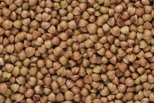 A full frame shot of raw, uncooked green buckwheat groats, showing their natural shape and texture for healthy food concepts.
