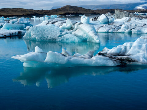 Icebergs of peculiar shapes floating in clean blue waters of Iceland's Jokulsarlon Glacier Lagoon