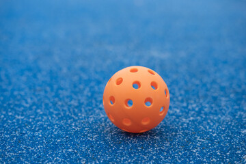Orange pickleball ball on blue court background The Concept of Contrast