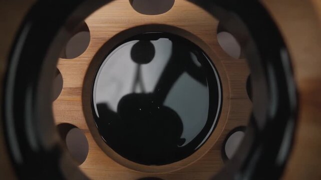 A close-up view of a wooden surface with a shiny black circular object