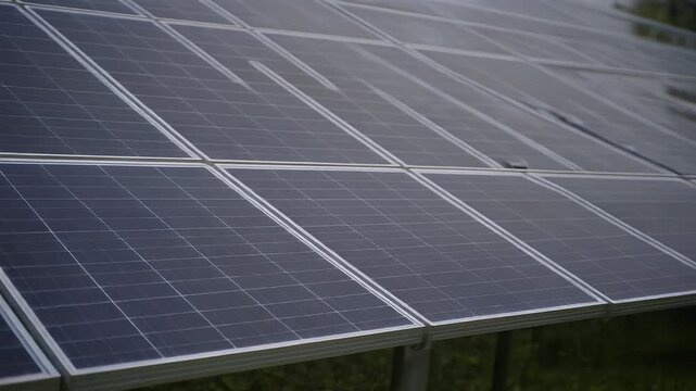 A close-up perspective of a series of dark rectangular panels with fine grids. Frames between are metallic, reflecting the sunlight