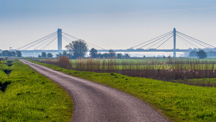 Fototapeta premium Rural road leading to cable stayed Tacitus bridge