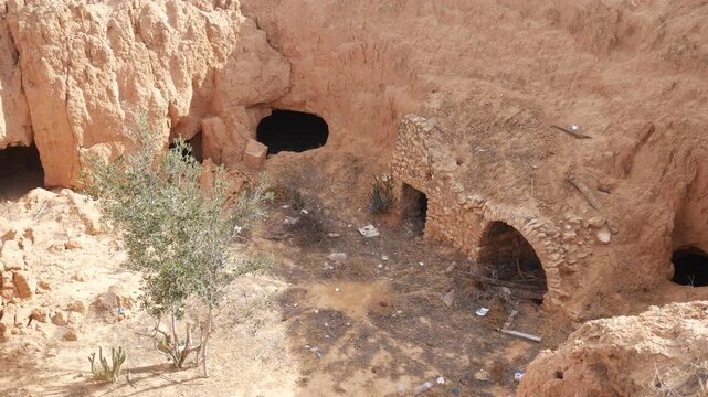 Panorama: Traditional troglodyte houses carved into rock in Matmata, Tunisia. Ancient underground dwellings in arid desert landscape, historic Berber architecture and cultural heritage site