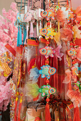 Fototapeta premium A vibrant display of hanging koi fish ornaments, tassels, and ribbons in pinks, reds, and oranges. Perfect festive decor for markets and Chinese New Year celebrations.