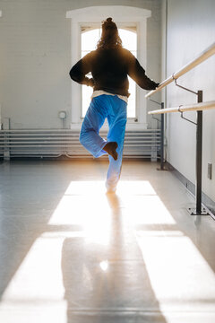 Dancer practicing ballet moves at sunny studio barre