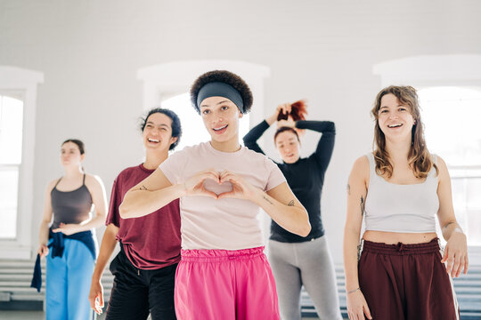 Diverse women forming a heart gesture with hands during dance class