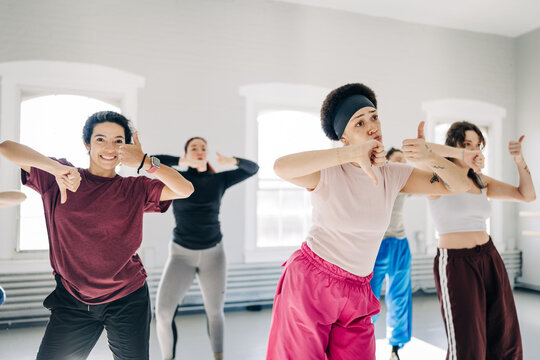 Diverse women showing thumbs up and thumbs down in dance class