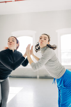 Two women mid-dance pressing hands together in sync