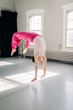 Female dancer performing a handspring in bright studio