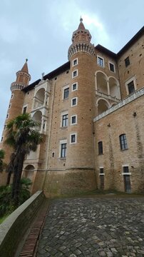 View of the Ducal Palace facade features the iconic twin towers (Torricini) and tiered loggias, showcasing Federico da Montefeltro's vision of Renaissance elegance and military power