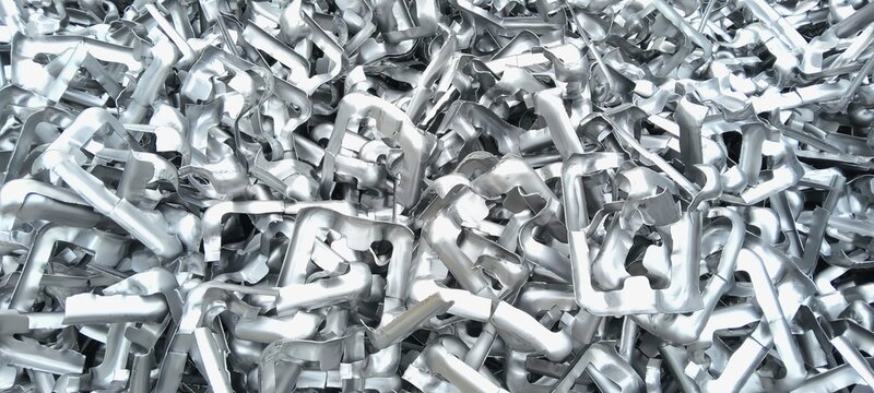 Pile of shiny industrial stainless steel scrap metal pieces for recycling process. High quality metallic texture and industrial waste background.