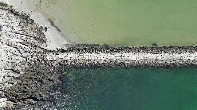 An aerial view showcases the serene meeting point of land and sea. The image captures the harmonious blend of textures and tones.