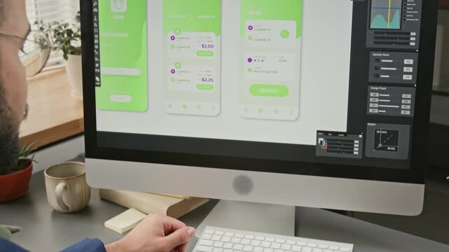 Medium close-up of young male UI developer drawing wireframe mockups with tablet and stylus in professional graphic editor software on computer monitor, developing e-commerce mobile application