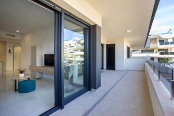 Naklejka premium Modern apartment balcony with glass railing and interior view through large sliding doors
