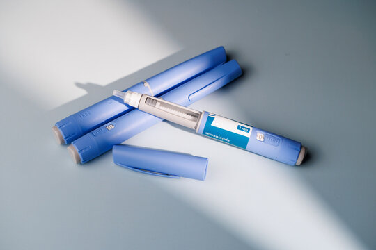 Close up of semaglutide GLP-1 pens for weight loss and diabetes treatment on a blue gradient background for healthcare and medicine.