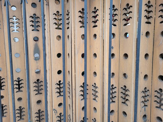 A fence made of carved beige wooden boards