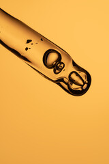 Face serum close-up on orange background. Collagen, hyaluronic acid for skin care. Achievements of...