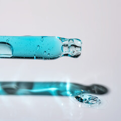Pipette and drops and smears of cosmetics. Liquid blue gel or a drop of serum on blue background.