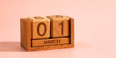 Wooden perpetual calendar showing March 1st date on wooden cubes, signifying the beginning of...
