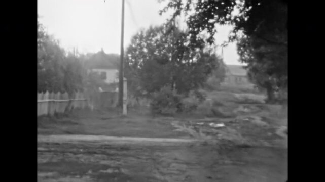 Sunny rural street in Ukrainian village in summer, black white Old film. Calm countryside nature. No people. Relaxed, calming village landscape. Rustic idyllic outdoor. Archival retro. Vintage archive