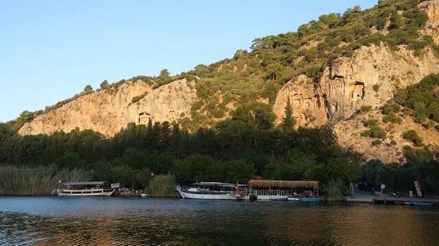 Sunset view of the Lycian King Tombs in the ancient city of Kaunos. Dalyan canal boats. Ortaca district, Mugla, T&uuml;rkiye. 4k video  