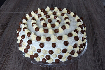 A minimalist homemade white birthday cake with chocolate balls and buttercream peaks, isometric view