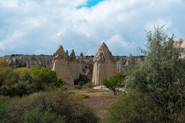 Fototapeta premium Wide landscape view of Love Valley Trail in Goreme, Cappadocia, Turkey Türkiye, featuring distinctive fairy chimney rock formations under a clear blue