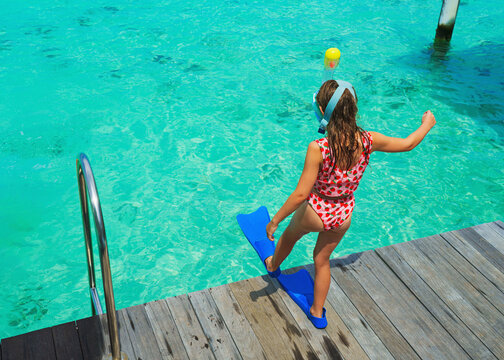 A girl on holiday, ready to dive in the crystal-clear water on a dream island, poster with copy space.