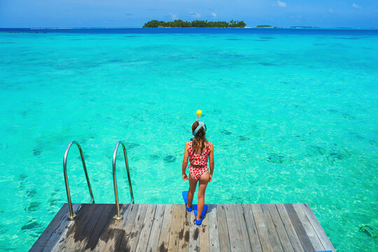 A girl on holiday, ready to dive in the crystal-clear water on a dream island, poster with copy space.