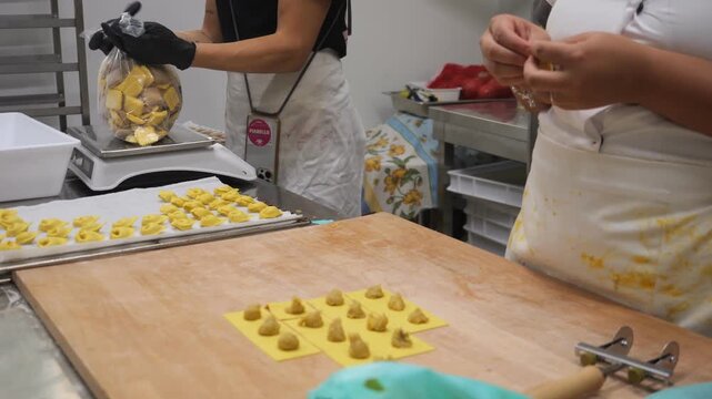 Women entrepreneurs meticulously crafting fresh tortelli pasta in a professional kitchen setting