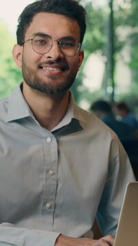 Indian businessman working with laptop technology Arabian ethnic business man using computer cyberspace network indoors in coworking office smiling looking at camera Muslim guy employer work online