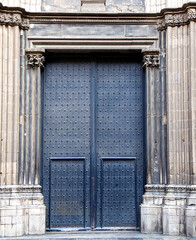 Ancient iron door with decorative knockers set in weathered stone wall creating historic architecture mood of strength protection and timeless heritage