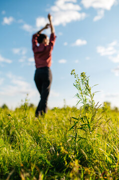 Silhouette of a young girl in a green summer meadow enjoying a sunny day