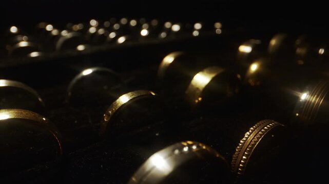 Camera sliding over rows of luxury gold wedding rings in a display box.