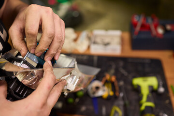Fototapeta premium Closeup of technician securing car headlight components. Focused shot showing technician carefully attaching and securing headlamp wiring to metal support with precision
