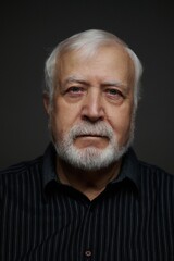 Obraz premium Elderly man poses for a close-up photo in a dark setting with focused lighting showing his features and expression clearly