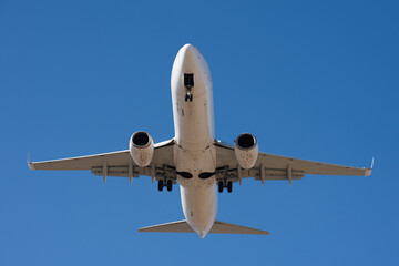The plane lands. Airplane, passengers flying in the blue sky, preparing to land at the airport. View from below