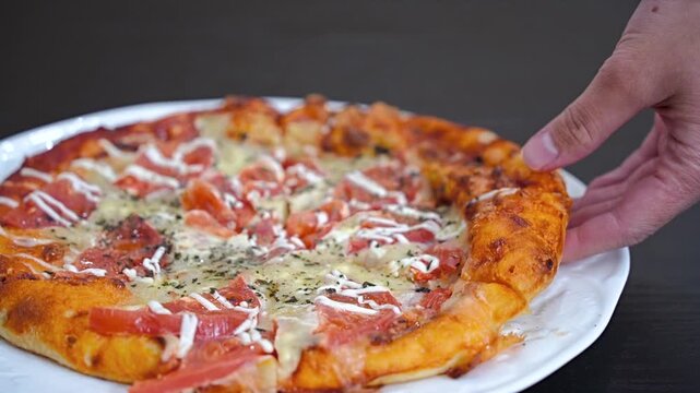 トマトいっぱいピザをもつ女性の手元