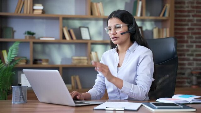 Young confident woman corporate operator in headset working in customer support service on helpline telesale talking using laptop in home office. Agent of call center advises clients online.