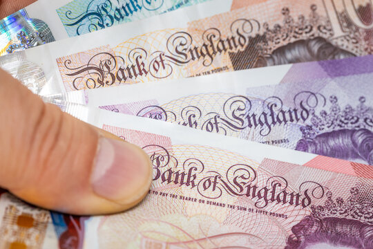 British pounds held in hand, macro close-up, Bank of England text. Close up