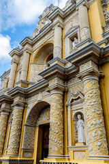 Obraz premium Iconic yellow facade of Convento de La Merced in Antigua Guatemala showcasing stunning Spanish Baroque architecture against a vibrant sky