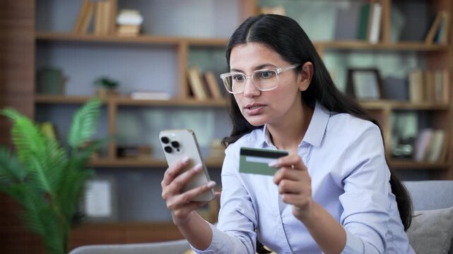 Shocked woman discovered fraud entering credit card number on mobile phone sitting on sofa in living room at home. Frustrated worried female became victim of deception money had been stolen. Close up