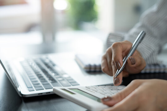 Close up business woman using calculator to calculate financial report, accounting on table at office, budget management. Doing finance, budgeting and tax calculation, monthly expenses